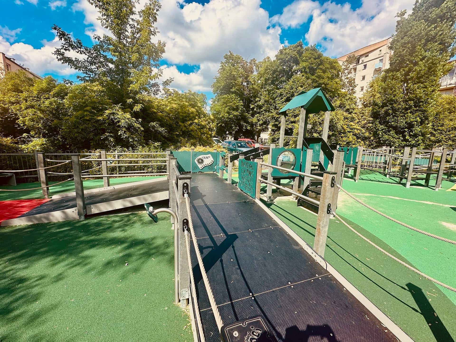 ire de jeux en plein air avec structures en matériaux recyclés, intégrée dans un environnement urbain et verdoyant